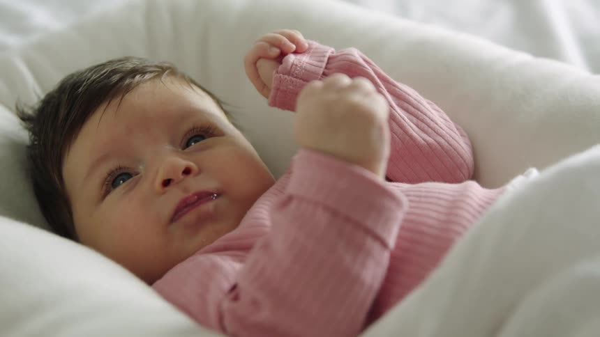 A baby girls lying down moving her arms around