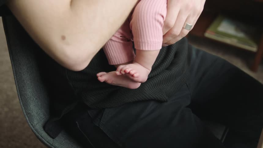 A father cradling a newborn while sitting in a chair at home