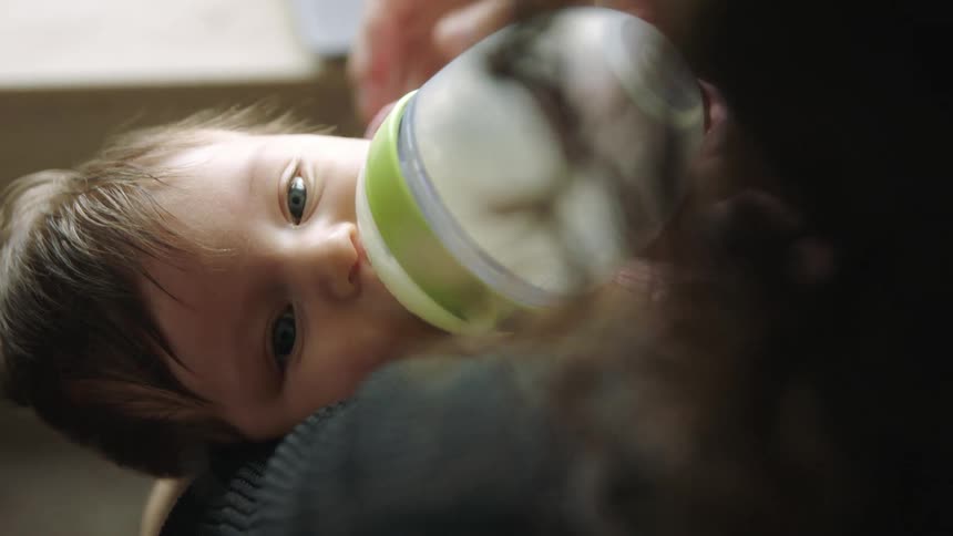 Mother holds child while feeding child with bottle