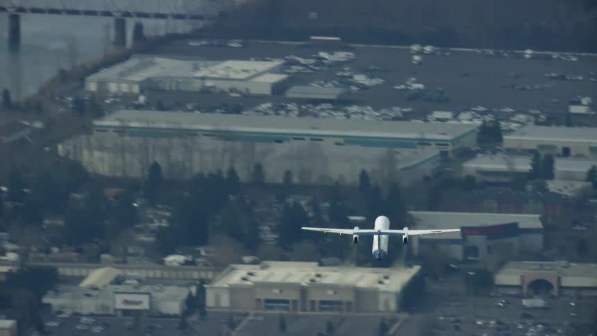 A Bombardier Q400, now the de Haviland of Canada Dash 8 400 commercial airplane flies over a large river after departing a major airport