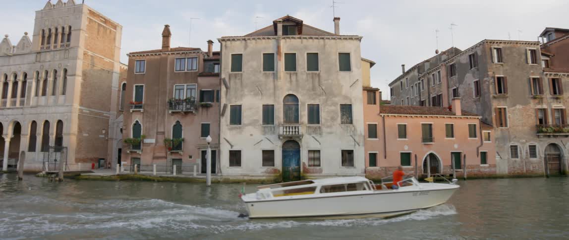 A boat drives past a building