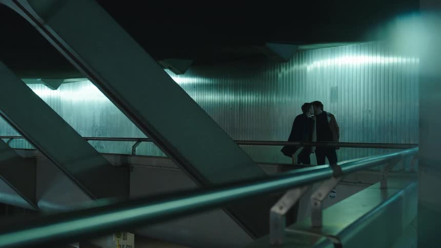 Two men kiss as they walk through a terminal
