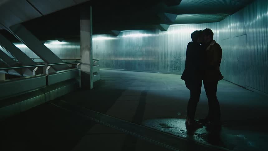 Two men are standing outdoors and kissing