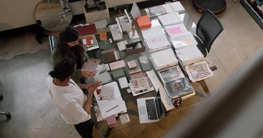 Employee showing customer samples of materials over the desk in an office