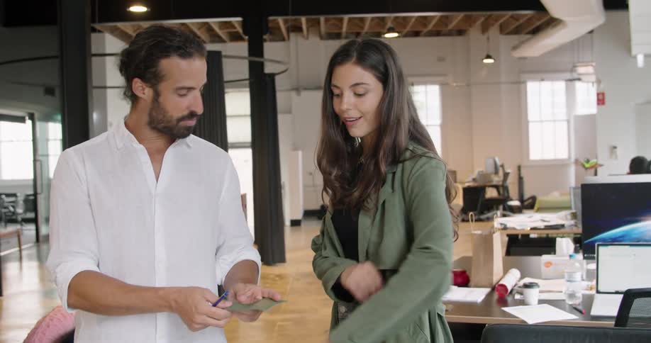 A man compares a piece of fabric to that of the jacket of his female coworker in an office during the day