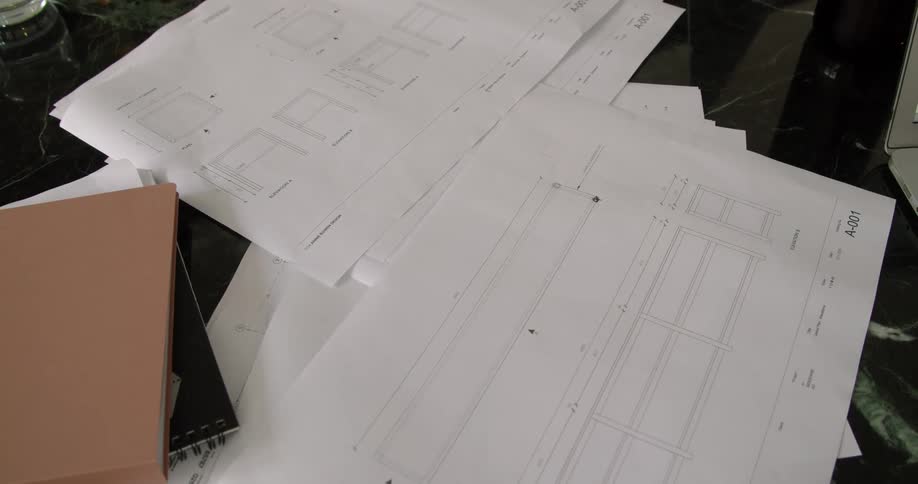 People at a desk writing on a paper with a pen and pencil