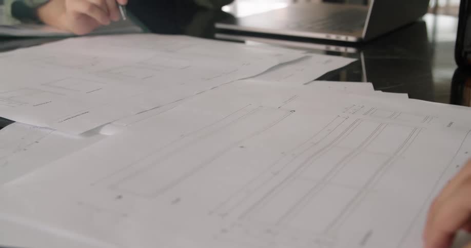 Two people working in an office making notes on paper graphs