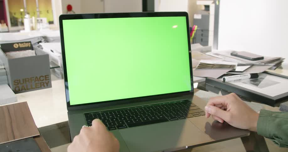 A person in a room sitting at a desk with a laptop