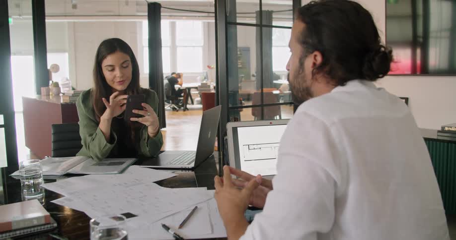 Two coworkers on laptops in an office setting