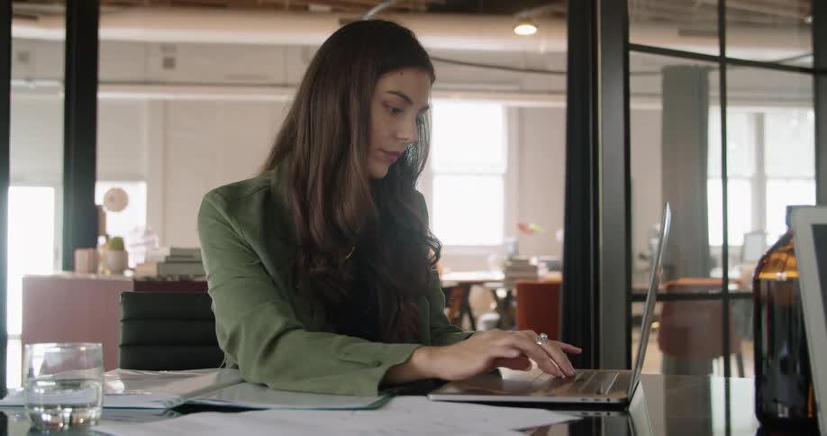 A woman is typing on a laptop and sitting at a table