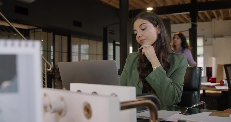 A woman sitting on a chair at a desk using a laptop