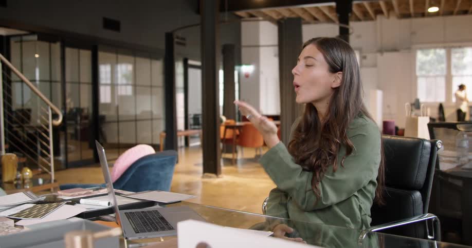 A woman smiling and blowing kisses while video chatting on a laptop