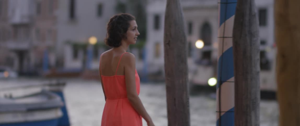 A woman walks by the water smiling