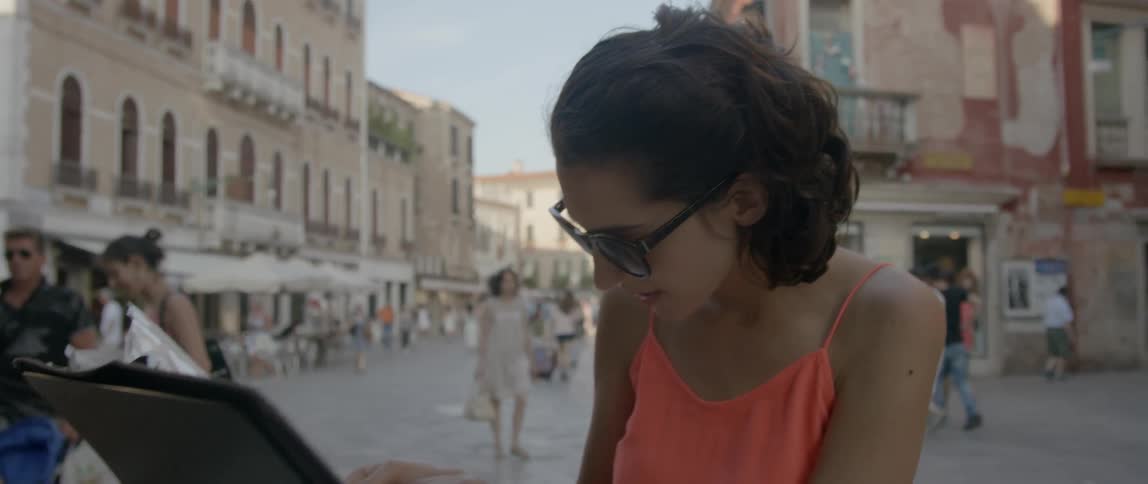 A woman in an orange shirt looks at a booklet