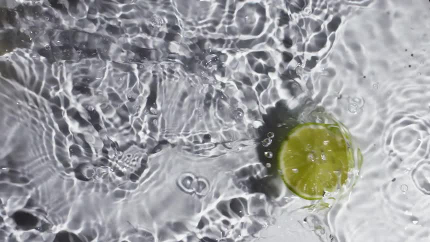 Two lemon slices sliding over water on a white background