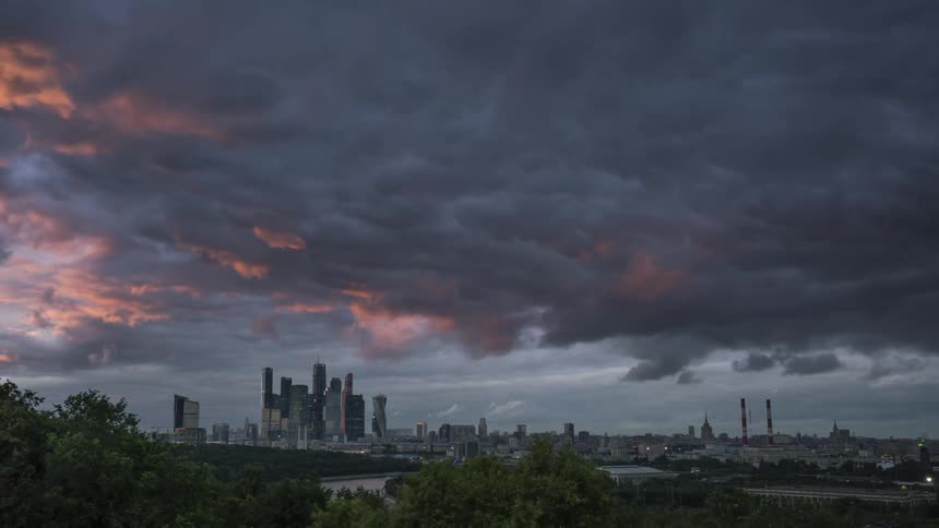 Timelapse of clouds rolling over the skyline of a city at sunset