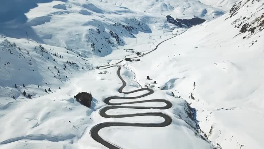 Winding curved road down the snow covered slopes of a mountain pass