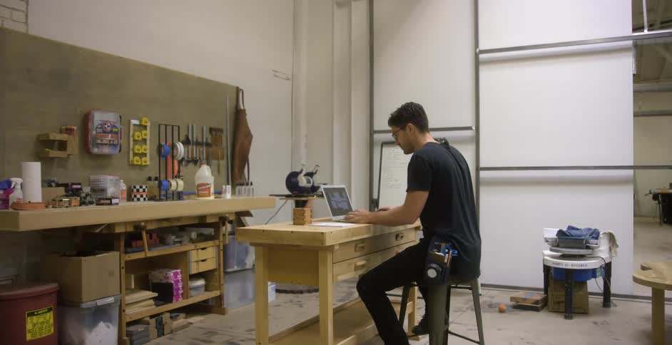Craftsman designing on his laptop in a workshop
