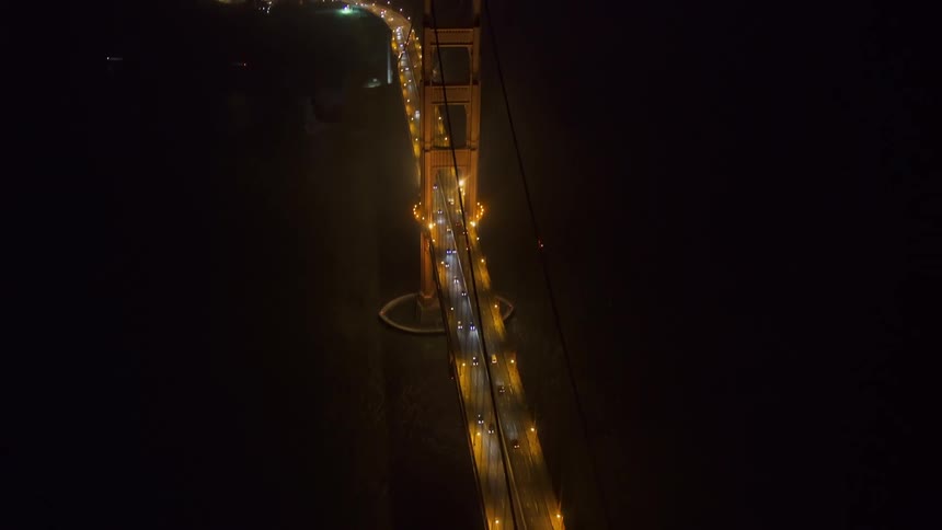Aerial view of a suspension bridge over a river near a waterfront city at night