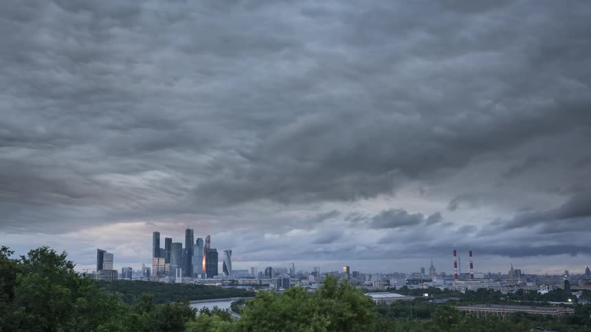 Timelapse of clouds rolling over the skyline of a city at evening