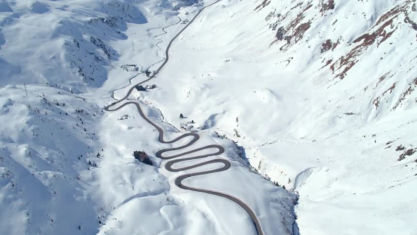 Cars travel on a winding road on a snow covered plateau