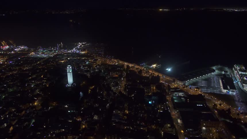 An aerial view of a skyline off the shore with cars traveling on a road and a cruise ship docked