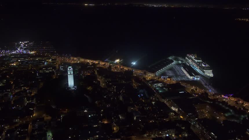 An aerial view of buildings in a skyline off the shore with a cruise ship parked at a pier