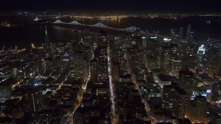 Aerial view of illuminated high rise buildings next to a river at night