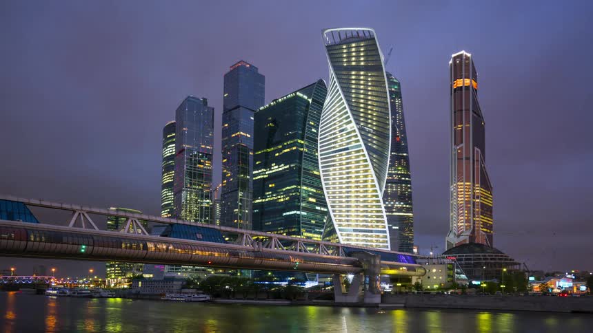 A cruise ship is docked down to downtown skyscrapers lit up at night