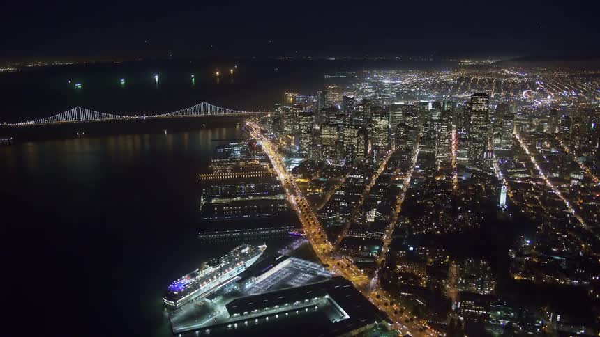 Aerial view of illuminated city with harbor next to river at night