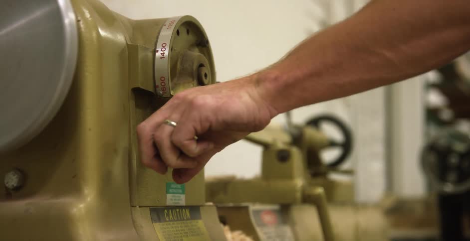 Man turning the handle on a lathe machine