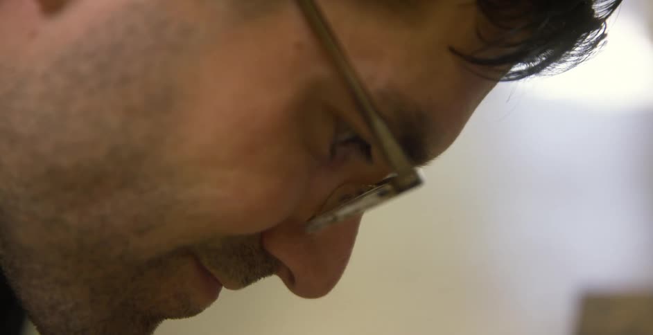 Closeup of a man wearing glasses focusing on a task