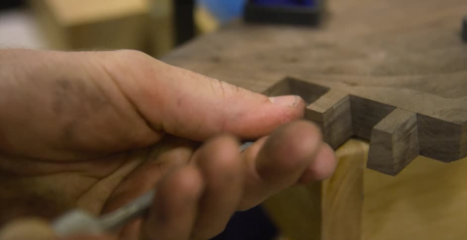 A man in a workshop chisels at wood