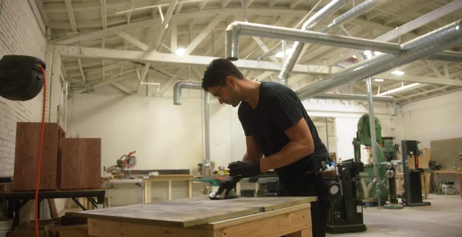 A man stains wood in a workshop
