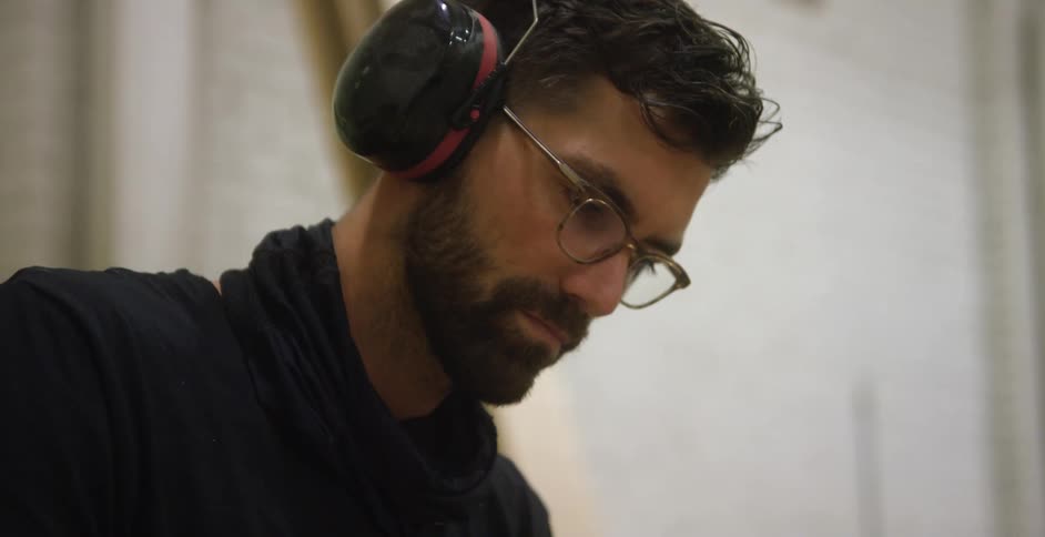 A man wearing a noise canceling headset inside of a building looking down