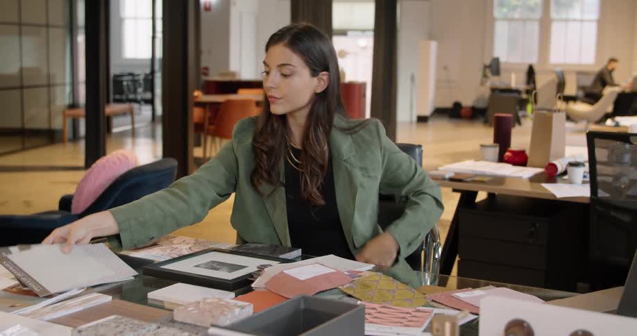 A woman sitting at a desk in front of a laptop computer sorting paperwork in an office