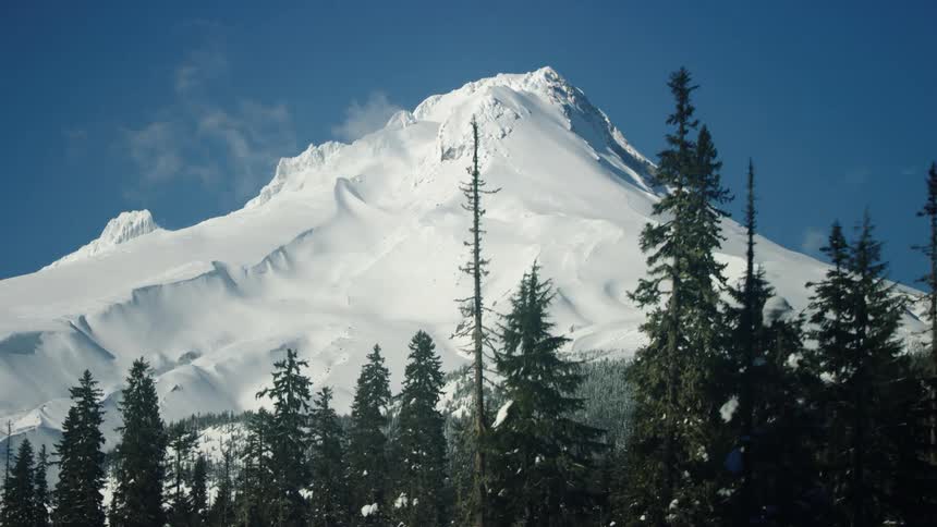 Mount Hood in winter is seen from this low altitude aerial tucked into the trees as the wind blows fiercely on the mountain
