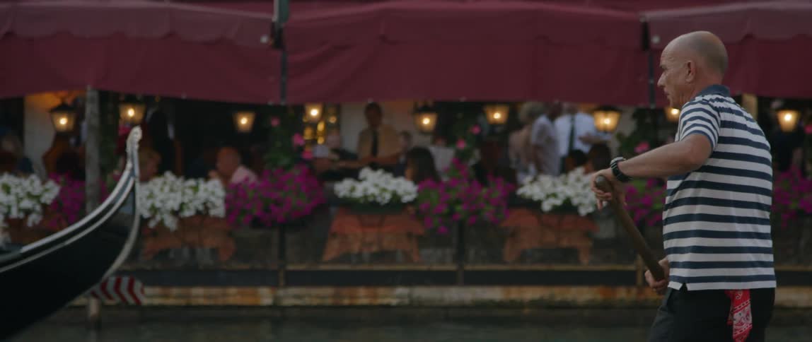 A man is rowing a boat before a restaurant