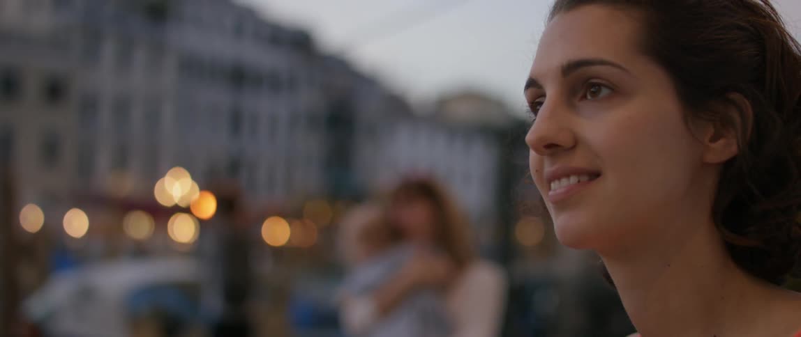 A woman stands smiling in a city setting