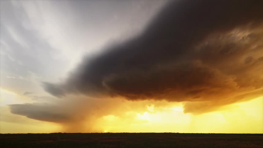 A time lapse reveals large storm clouds swirling across the sky at sunset