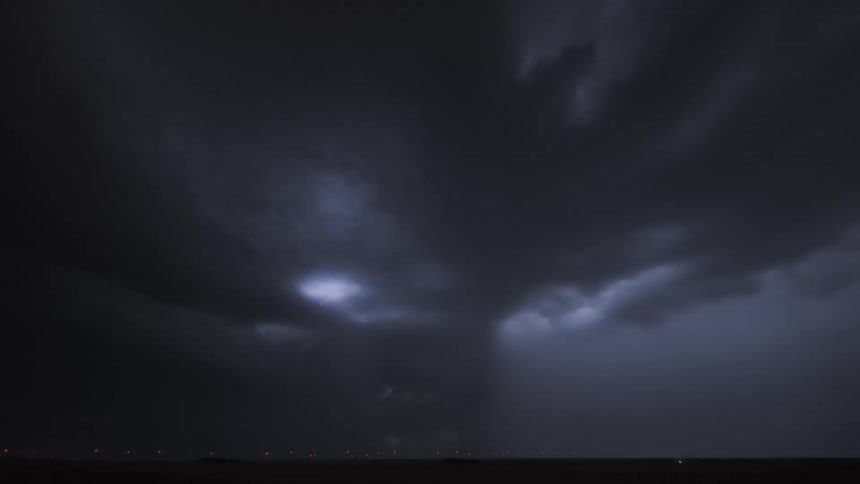 Lightning flashes from dark storm clouds in the night sky