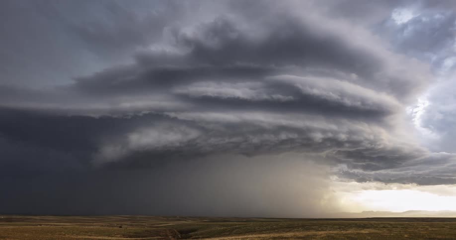 Swirls of storm clouds forming a tornado rolling over an empty field