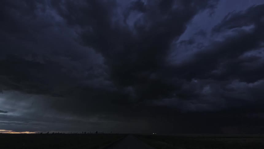 Storm front flowing across countryside turns day dark