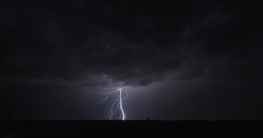 Multiple lightning strikes hit ground from dark clouds at night