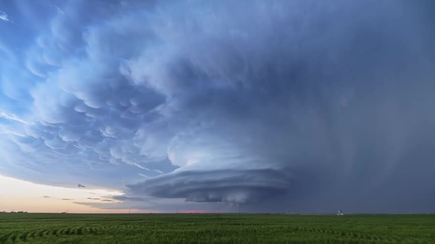 Thunderclouds swirl over a vast grassland in the countryside during the day