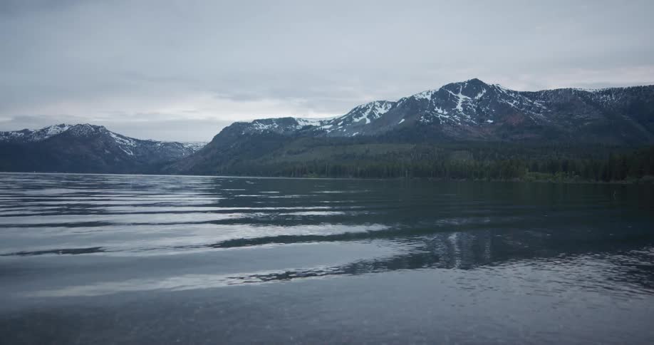 Small waves on the surface of a lake near the snow covered peaks of a mountain range
