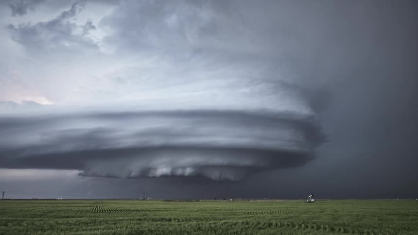 Lightning flashes from dark tornado clouds spinning in the air over farmland