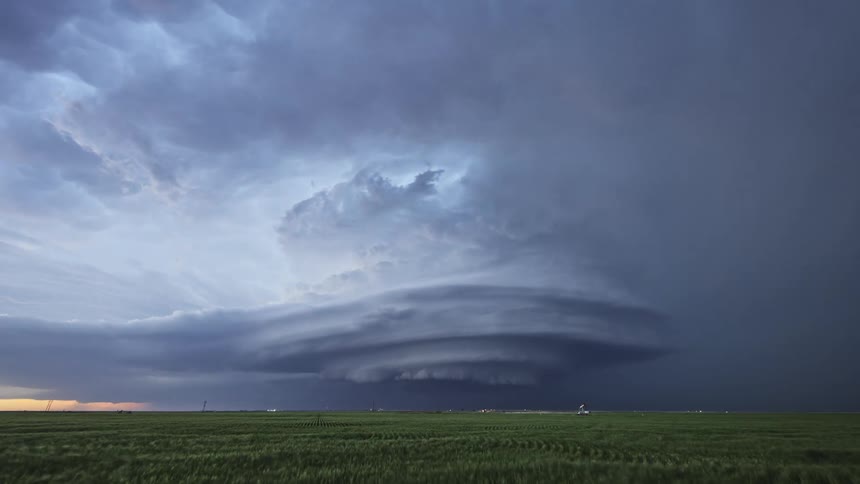 Lighting flashes from tornado clouds spinning in the air over farmland
