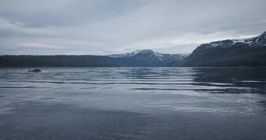 Small waves on the surface of a lake near the snow covered peaks of a mountain range