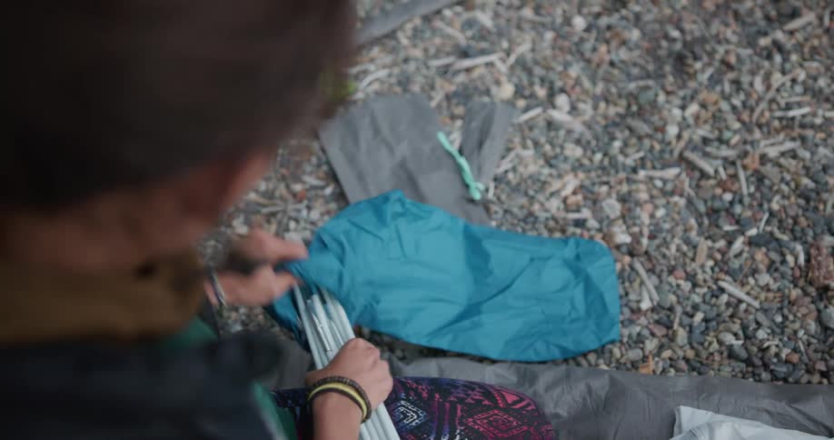 A woman putting away tent poles